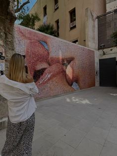 a woman taking a photo of a painting on the side of a building