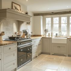 a kitchen with an oven, dishwasher, sink and window in the background