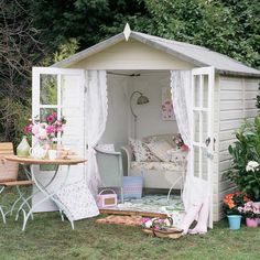 a small white shed sitting on top of a lush green field