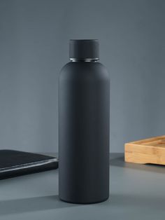 a black water bottle sitting on top of a table next to a wooden cutting board