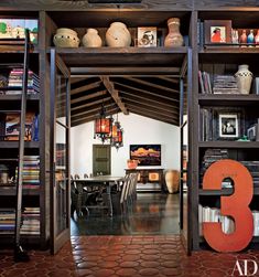 an open book shelf with books and vases on top of it in the middle of a room