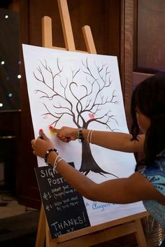 a woman is painting a tree on an easel with chalk and pencils in front of her