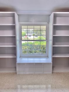 an empty room with shelves and a window