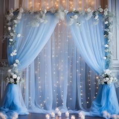 a blue and white wedding arch decorated with flowers, candles and lights in front of a sheer curtain