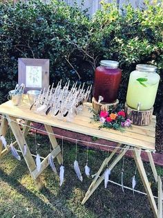 a wooden table topped with lots of glasses next to a vase filled with flowers and feathers