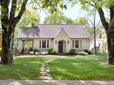 a white house surrounded by trees and grass with a stone path leading to the front door