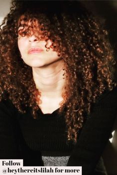 a woman with long curly hair wearing a black sweater