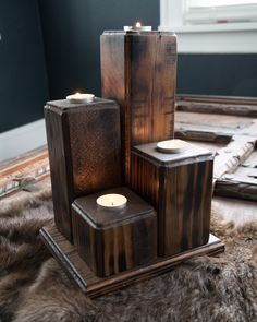 candles are placed in wooden boxes on a fur rug next to a mirror and window