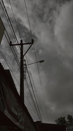 black and white photo of power lines in the sky with clouds above it, on a cloudy day