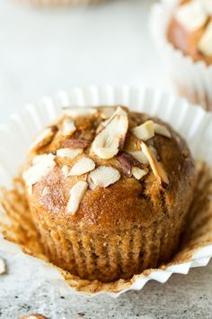 a muffin with almonds on top in a paper cupcake liner sitting on a table