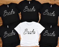 Bride Squad Hen Party T-shirts. Hen party Tees Bride Tribe, Team Bride, Bridal Party Shirts, Bachelorette T-shirts. Wedding tops Hen night. Introducing our fabulous Hen Party T-shirt in Classic Black and white! Made with love from 100% cotton, this tee is the perfect addition to any bride and bridesmaid squad, ensuring you look and feel incredible during all your pre-wedding celebrations.  The bride's shirt is a classic white with a beautiful black print. The other hen party members' t-shirts are a stylish Black colour with a striking White print. These shirts are not only fashionable but also practical, as they can be worn by both men and women in your group so can give a relaxed fit feel. - Custom: Each t-shirt is carefully handmade to match your bridal party's unique style. We pay atten Fitted White Top For Bridesmaid, White Fitted Top For Bridesmaids, White Fitted T-shirt For Bachelorette Party, White Crew Neck Top For Bridesmaids, White Letter Print Top For Bachelorette Party, White Short Sleeve Top For Hen Party, White Short Sleeve Top For Bridal Shower, Fitted White Top For Bridal Shower, White Fitted Top For Bridal Shower