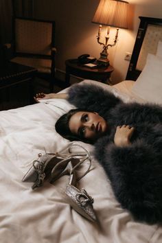 a woman laying on top of a bed next to two pairs of shoes and a lamp