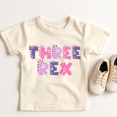 there is a pair of shoes next to a t - shirt with the words three rex on it