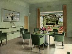 a dining room with green chairs and a round glass table in the middle of it