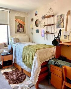 a bed room with a neatly made bed next to a desk and guitar on the wall