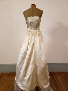 "1950s, 34\"bust,wedding ensemble consists of gown and coat of egg shell white rayon slipper satin. Gown has crystal beading at bosom, in a bow motif. Bodice of gown is strapless, with stays sewn into the interior of bodice, bodice comes to a point at waist. Skirt is full, fuller in back, and a bit longer in back than front. Coat has rounded lapels, buttons at mid section with 5 round satin buttons. Skirt of coat is floor length in front, with a cathedral length train in back. Faux pockets are a Cream Ball Gown For Debutante Ball, Regency Style Ball Gown For Vintage Events, Vintage White Evening Dress For Wedding, Classic Silk Evening Dress For Weddings, Silk Evening Dress With Lined Bodice For Wedding, Vintage White Wedding Evening Dress, Silk Wedding Evening Dress With Lined Bodice, Cream Ball Gown For Formal Occasions, Cream Ball Gown For Evening