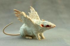 a toy rat with wings on it's back sitting on a table next to a gray background