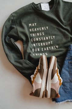 a pair of sneakers, sweatshirt and ripped jeans sitting on top of a white surface