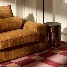 a couch sitting on top of a checkered floor next to a table with a vase