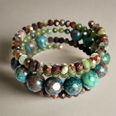 Shades of green, blue, and brown dominate this beaded coil wrap bracelet. Faceted chrysoprase, round jade, and African turquoise come together in a medley of tone and texture in this done-for-you stack. I love the earth tones and contrast of size, color, and texture in this one-of-a-kind bracelet. 4mm round jade 4x5mm faceted chrysoprase 10mm African turqouise one size fits most - best for small to medium wrists Handmade in Lincoln, Nebraska Artisan Turquoise Hand Wrapped Wrap Bracelet, Artisan Hand Wrapped Turquoise Wrap Bracelet, Rustic Hand-wrapped Bracelet With Round Beads, Bohemian Wrap Bracelet With Faceted Round Beads, Bohemian Beaded Wrap Bracelet For Layering, Bohemian Turquoise Gemstone Beads Wrap Bracelet, Bohemian Turquoise Wrap Bracelet With Gemstone Beads, Bohemian Wrap Bracelet For Layering, Green Gemstone Beads Bohemian Wrap Bracelet