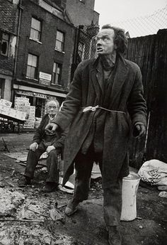 black and white photograph of two men in an alleyway, one holding a bucket