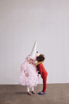 two children dressed in costumes standing next to each other and one is wearing a cone