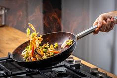 someone is frying vegetables in a wok on top of the gas burner