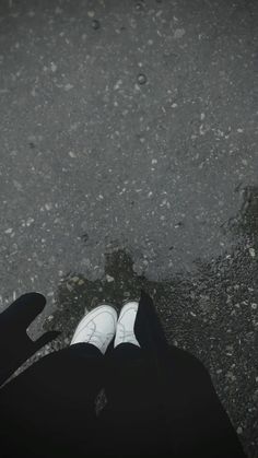 a person standing in the street with their feet on the ground and looking down at them