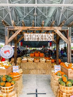 an outdoor market with pumpkins and squash in wooden baskets on display under a metal roof