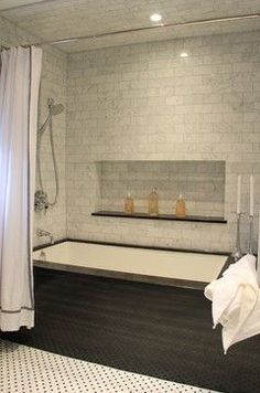 a bath tub sitting under a window next to a shower