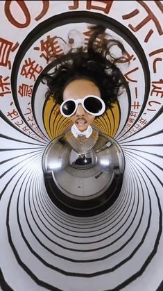 the reflection of a woman with sunglasses on her face is seen through a circular object