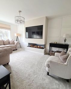 a living room with couches, chairs and a flat screen tv on the wall