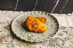 two pieces of fried chicken on a plate with parsley sprinkled around the edges