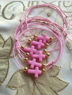 four pink bracelets with gold balls and beads on a tablecloth covered surface,