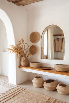 a white room with baskets and mirrors on the wall next to a shelf filled with vases