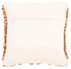 an orange and white pillow with pom poms on the edges, sitting against a white background