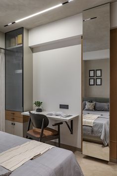 a bedroom with a bed, desk and mirror on the wall next to each other