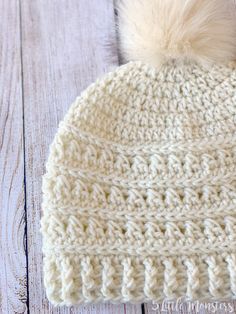 a white knitted hat with a pom - pom sitting on top of it