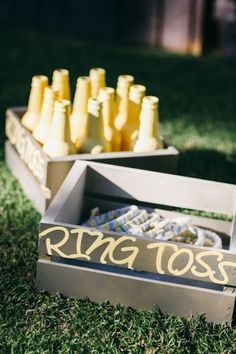 a wooden box filled with yellow bottles sitting on top of a lush green field