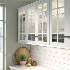 a kitchen with white cabinets and wooden counter top next to a potted plant on a window sill