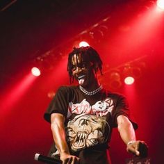 a man with dreadlocks standing on stage holding a microphone and wearing a t - shirt