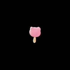 a pink gummy bear lollypop on a stick against a black background in the dark