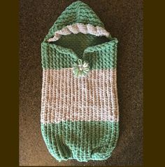 a green and white knitted sweater laying on top of a brown carpeted floor