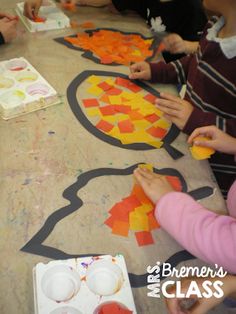 several children are sitting at a table making crafts