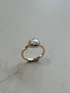 A take on our super popular Silver Linings Cloud Ring and made with a mini keshi pearl set in recycled 9ct gold on a 1.8mm band. Each pearl will be similar in shape, size and quality to the example photos given. The pearl will be around 10mm making it super dainty and perfect for everyday wear. Every pearl in our collection has beautiful iridescence and unique textures. This ring is available in a range of textures (hammered or regular) Please note: This piece may take a little long to complete than the time advertised as it requires hallmarking by law.  Also available in silver, see our Mini Cloud Ring. 14k Gold Pearl Ring With High Luster, High Luster 14k Gold Pearl Ring As Gift, Minimalist Polished Moonstone Ring For Wedding, Minimalist Polished Moonstone Wedding Ring, Minimalist Moonstone Ring With Polished Finish For Wedding, Minimalist 14k Gold Oval Pearl Ring, Minimalist Oval Yellow Gold Pearl Ring, 14k Gold Pearl Ring With Rose Cut Diamonds, Minimalist Yellow Gold Pearl Ring In Sterling Silver