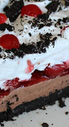 a piece of chocolate cake with whipped cream, cherries and oreo cookies on top