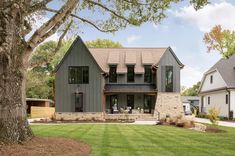 a large house sitting on top of a lush green field next to a tall tree