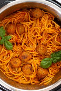 spaghetti with meatballs and basil leaves in an instant pot on the stove top, ready to be cooked