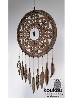 a circular wooden wind chime with feathers hanging from it's sides and an owl on the other side