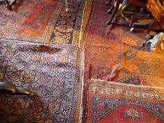 an old rug is laying on the floor next to a chair and other antique furniture